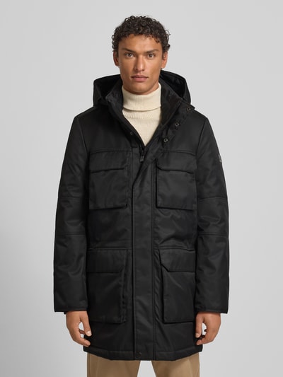 Männermodel trägt Jacke mit Pattentaschen Modell von NAUTGÅRD, Regular-Fit, Kapuze, Schwarz, Größe M, Ganzkörperansicht von vorne.