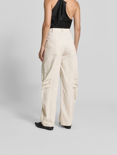 Kobiece modelka nosi Hose aus Leinen-Mix od ROTATE, jasny len z zakładkami, kieszenie, krój balloon fit, szerokie nogawki, zapięcie na hak i zamek, długość nogawki 81 cm, szerokość w rozmiarze 36: 36 cm, widok całej sylwetki z tyłu