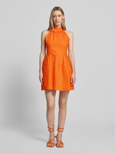 Frauenmodel trägt Cocktailkleid mit Stehkragen und rückseitigem Knopfverschluss von Little Mistress aus reiner Baumwolle in A-Linie als Minikleid in leuchtendem Orange, Stoff wirkt glatt, Ganzkörperansicht von vorne. Rückenlänge bei Größe 36: 84 cm, Brustweite: 42 cm.