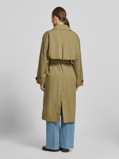 Vrouwenmodel draagt 'Trenchcoat mit verdecktem Verschluss und Bindegürtel' van Blonde No. 8 van katoenmix in getailleerd model met platte kraag, strikceintuur, zij-steekzakken en knopen, kleur olijfgroen, ruglengte bij maat 36: 113 cm, schouderbreedte: 60 cm, borstwijdte: 54 cm, mouwlengte: 49 cm. Ganzkörperaanzicht rugaanzicht.
