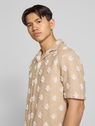 Männermodel trägt Regular Fit Freizeithemd mit Strukturmuster und Kentkragen von REVIEW im Baumwoll-Mix, Nahaufnahme Oberkörper. Rückenlänge 70 cm, Schulterbreite 58 cm, Ärmellänge 28 cm, beige Grundfarbe mit auffälligem Strukturmuster.
