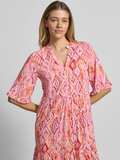 Frauenmodel trägt Ausgestelltes Maxikleid aus reiner Viskose Modell 'EASY JOY' von Vero Moda mit Allover-Muster in Rosa und Orange, 1/2-Arm, Henley-Ausschnitt, Raffung und kurzer Knopfleiste, Nahaufnahme Oberkörper.