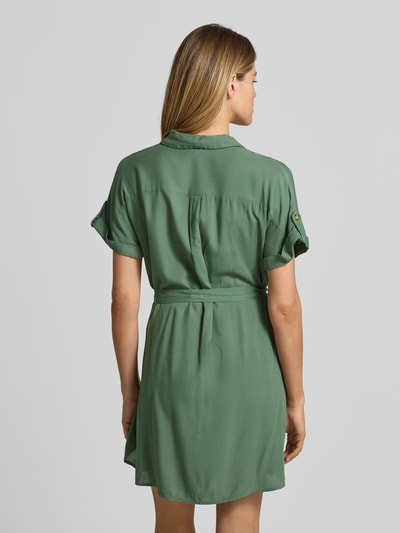 Frauenmodel trägt Fließendes Freizeitkleid aus reiner Viskose Modell 'BUMPY' von Vero Moda in Uni-Grün, Mini-Länge, kurzarm, Popeline, Ganzkörperansicht Rückansicht.