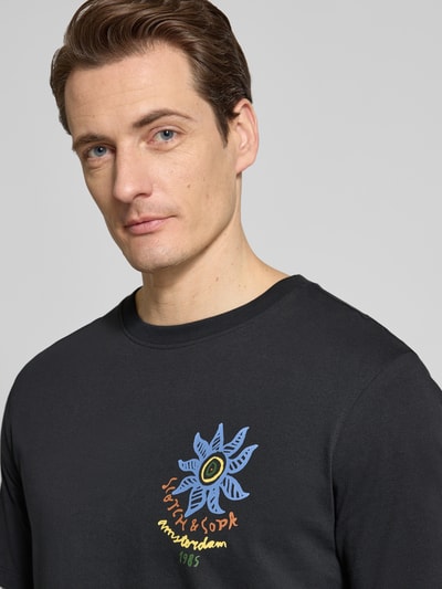 Männermodel trägt T-Shirt mit Label-Prints und Rundhalsausschnitt von Scotch & Soda aus reiner Baumwolle, Regular-Fit, Nahaufnahme Oberkörper.