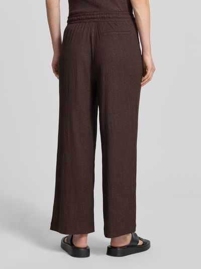 Frauenmodel trägt Wide Fit Stoffhose mit Strukturmuster Modell 'Mileni' von OPUS in Dunkelbraun, Elastischer-Material-Mix, Eingrifftaschen, Elastischer Bund mit Tunnelzug, Damen Stoffhose, Ganzkörperansicht Rückansicht.