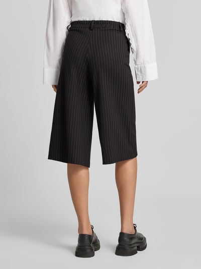 Frauenmodel trägt Regular Fit Culotte mit Bundfalten Modell 'SC-GILL 3' von Soyaconcept in Schwarz mit Nadelstreifen, 3/4-Länge, Ganzkörperansicht Rückansicht.