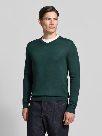 Männermodel trägt Strickpullover aus Woll-Mix mit V-Ausschnitt von Christian Berg Men in Dunkelgrün, Regular Fit, gerippte Abschlüsse, Ganzkörperansicht von vorne.
