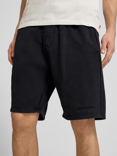Männermodel trägt Shorts mit elastischem Bund und Logo-Stitching von Pegador, Schwarz, Baumwoll-Mix, Loose-Fit, Nahaufnahme Oberschenkel.