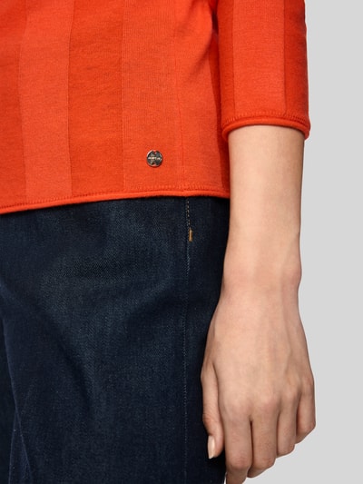 Frauenmodel trägt Strickpullover aus Schurwolle-Mix mit Stehkragen von Marc Cain, rot, Label-Detail, Nahaufnahme Oberkörper, Slim Fit, Kaschmir-Anteil, Rückenlänge 55 cm, Ärmellänge 66 cm.