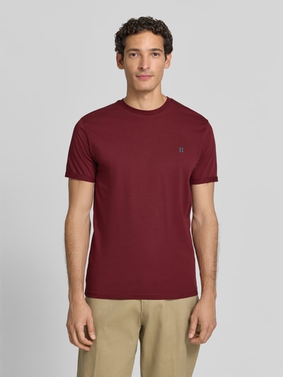 Männermodel trägt T-Shirt mit Logo-Stitching und Rundhalsausschnitt von Les Deux, Baumwoll-Mix mit Stretch-Anteil, Straight Fit, Ganzkörperansicht von vorne.