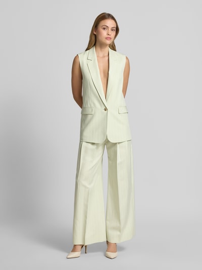 Frauenmodel trägt Loose Fit Weite Hose mit Leinen-Anteil Modell 'TAKORA' von BOSS Orange im Nadelstreifen-Muster, Twill-Struktur, Ganzkörperansicht von vorne.