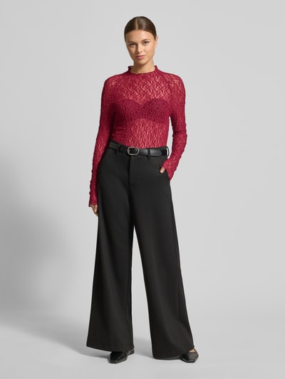 Frauenmodel trägt Slim Fit Longsleeve in semitransparentem Design von Marc Cain in Rot mit Rundhalsausschnitt, kombiniert zu schwarzer weiter Hose, Ganzkörperansicht von vorne.