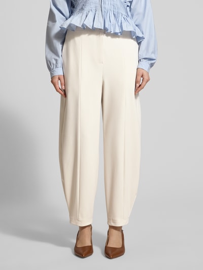 Frauenmodel trägt Bundfaltenhose in verkürzter Passform Modell 'ODINE' von Raffaello Rossi im soften Creme-Ton, Material-Mix mit Stretch-Anteil, lockerer Schnitt, französische Eingrifftaschen, Knopf- und Reißverschluss, Ganzkörperansicht von vorne.