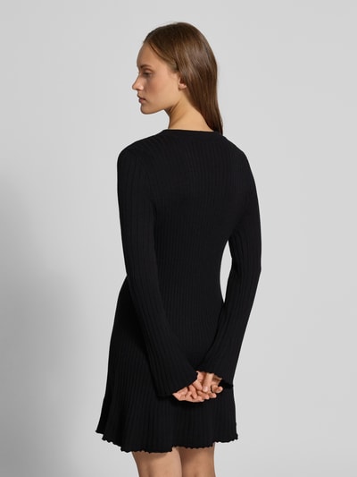 Frauenmodel trägt Eng anliegendes Freizeitkleid aus Viskose-Mix Modell 'MICHELLA' von ONLY, schwarze, gerippte Textur, Ganzkörperansicht Rückansicht, Damen Strickkleid von ONLY.