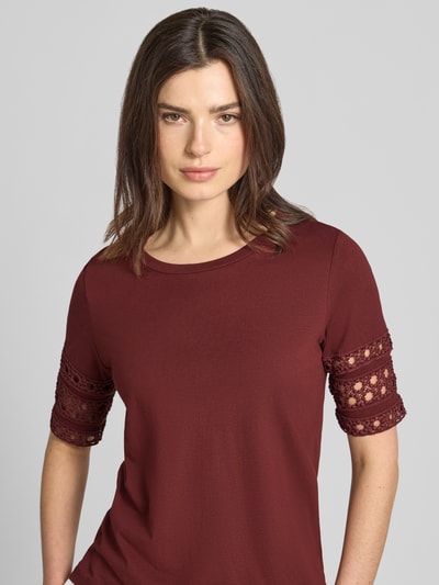 Vrouwenmodel draagt Regular Fit T-shirt uit pure katoen model 'IVACY' van Vero Moda, effen bordeauxrood met kantapplicaties, ronde hals, korte mouw, detailopname bovenlichaam.