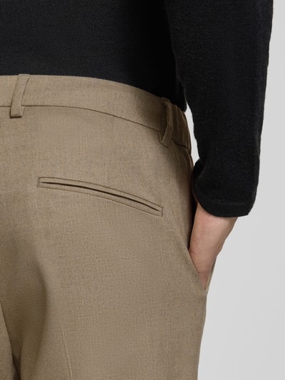 Männermodel trägt beige Straight Fit Stoffhose mit Viskose-Anteil Modell 'Ajend' von DRYKORN, leichte Struktur, Nahaufnahme Rückansicht. Elastischer Material-Mix, Knopf- und Reißverschluss sind Teil der Stoffhose.