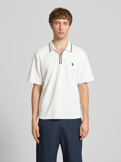 Männermodel trägt Regular Fit Poloshirt mit Reißverschluss und Label-Stitching von REVIEW, Material-Mix, Strukturmuster, Ganzkörperansicht von vorne.