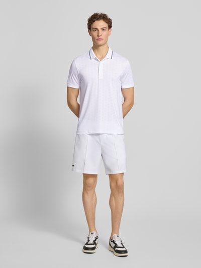 Männermodel trägt Regular Fit Sport Poloshirt mit Kontraststreifen von Lacoste Sport, weiß, unifarben, Stretch-Webstruktur, Ganzkörperansicht von vorne.