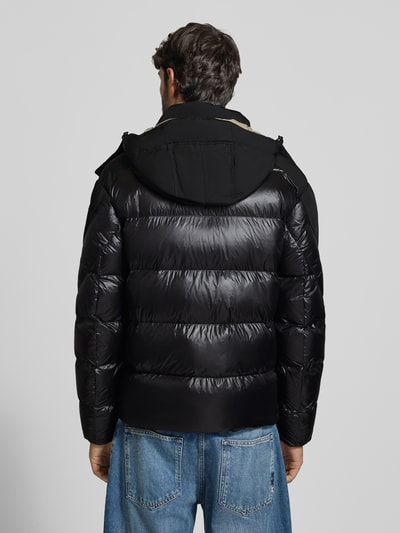 Männermodel trägt Steppjacke mit Zweiwege-Reißverschluss Modell 'KIERNAN' von Blauer USA, Farbe schwarz, Kapuze, krój regular fit, label-detail, Szerokość w rozmiarze M: 59 cm, długość tyłu: 67 cm, szerokość ramion: 49 cm, długość rękawa: 65 cm, widok całej sylwetki z tyłu.