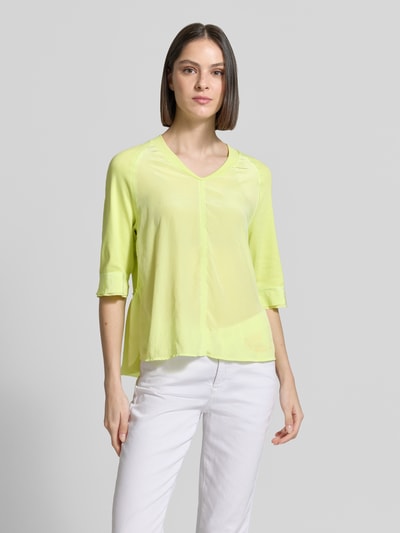Modelka nosi damski t-shirt 'T-Shirt mit V-Ausschnitt und 3/4-Arm' od Marc Cain, mieszanka bawełny i elastanu, krój relaxed fit, dekolt w serek, rękaw o dł. 3/4, długość tyłu w rozmiarze 36: 60 cm, jasny żółty kolor, gładka faktura, widok całej sylwetki z przodu.