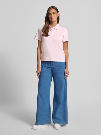 Modelka nosi Regular Fit Poloshirt aus Baumwoll-Mix von s.Oliver RED LABEL w jednolitym jasnoróżowym kolorze, piqué, krótkie rękawy, polo kołnierzyk, krój regular fit, bawełniany miks, widok całej sylwetki z przodu.