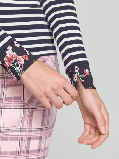 Kobieta modelka nosi Slim Fit Longsleeve aus Baumwoll-Mix od Marc Cain, granatowo-białe paski, florale detale, mieszanka bawełny, krój slim fit, okrągły dekolt, długość tyłu w rozmiarze 36: 57 cm, zbliżenie na rękaw.