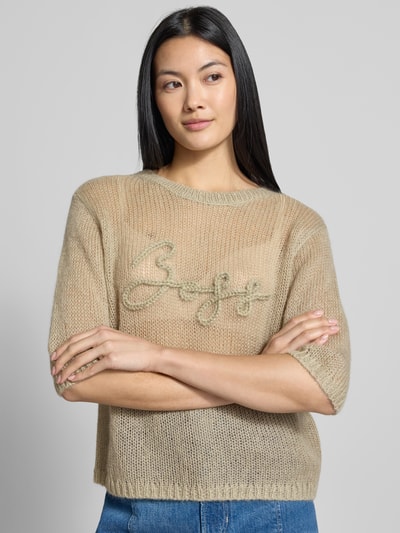 Frauenmodel trägt Regular Fit Pullover aus Schurwoll-Modal-Mix Modell 'C_Farezza' von BOSS für Damen von BOSS Orange in Beige mit grober Strickstruktur und gesticktem Logo, Nahaufnahme Oberkörper.