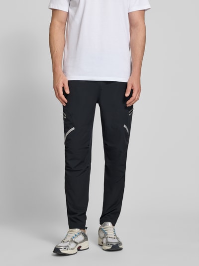 Männermodel trägt schwarze Regular Fit Sweatpants mit Logo-Print Modell 'Unstoppable' von Under Armour, Cargo-Taschen, Elastischer-Material-Mix, Herren, Ganzkörperansicht von vorne.