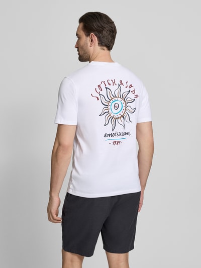 Männermodel trägt T-Shirt mit Label-Print und Rundhalsausschnitt von Scotch & Soda, Reine Baumwolle, Regular-Fit, Rückenlänge 70 cm, Größe M, weiß mit farbigem Print, Ganzkörperansicht Rückansicht.