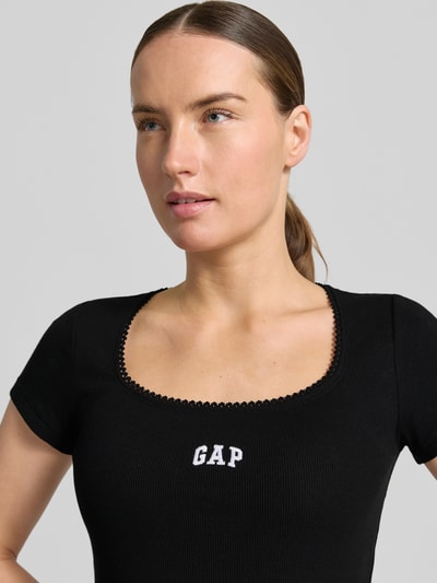 Frauenmodel trägt T-Shirt mit Logo-Stitching von GAP in Schwarz, Baumwoll-Mix mit Stretch-Anteil, Rundhalsausschnitt, Körpernahe Passform, Nahaufnahme Oberkörper.
