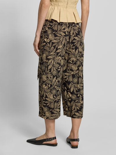 Frauenmodel trägt Culotte aus Viskose mit Bindegürtel von Apricot im Culotte-Stil, Reine Viskose, Wide Leg Fit, Elastischer Bund, französische Eingrifftaschen, Bundweite bei Größe S: 33 cm, Innenbeinlänge bei Größe S: 50 cm, florales Muster in Schwarz und Gold, Ganzkörperansicht Rückansicht.