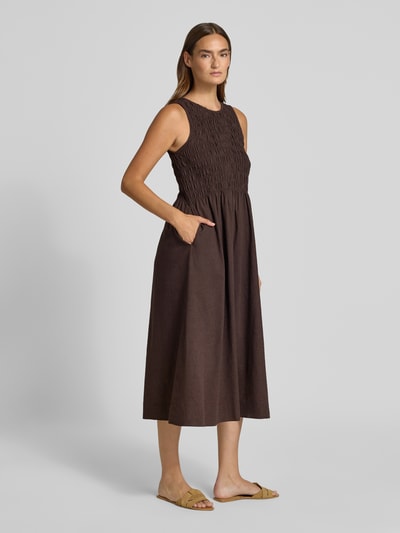 Frauenmodel trägt Midikleid aus Baumwoll-Leinen-Mix mit Eingrifftaschen von Smith and Soul in Braun, taillierte Passform, Rundhalsausschnitt, rückseitiger Schlüsselloch-Ausschnitt, Rückenlänge 120 cm, Brustweite 36 cm, Ganzkörperansicht von vorne.