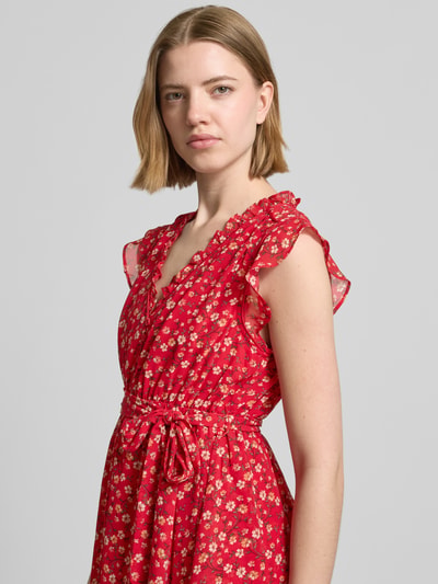 Frauenmodel trägt Minikleid mit floralem Allover-Print von Apricot in Rot mit Rüschenbesatz, V-Ausschnitt, Tailliert, abnehmbares Taillenband, Ärmelloses-Design, Ganzkörperansicht von vorne.