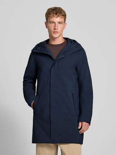 Männermodel trägt Regular Fit Mantel mit Kapuze Modell 'Brussel' von Helly Hansen in Dunkelblau, glatte Textur, Ganzkörperansicht von vorne. Rückenlänge 96 cm, Schulterbreite 46 cm, Brustweite 51 cm, Ärmellänge 66 cm.