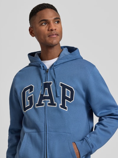 Männermodel trägt 'Sweatjacke mit Logo und Känguru-Tasche' von GAP in blauw katoenmix, regular fit, ritssluiting, kangoeroezak, logoprint, Nahaufnahme Oberkörper.