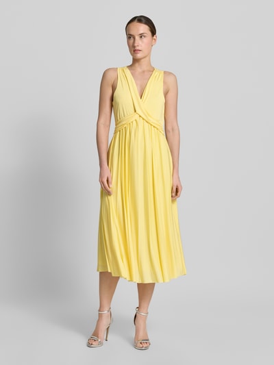 Frauenmodel trägt Abendkleid mit V-Ausschnitt Modell 'Amanda' von GUIDO MARIA KRETSCHMER WOMAN aus gelbem Satin, Taillierter Schnitt, Midikleid, Raffungen, Rückseitiger Schlüsselloch-Ausschnitt, glatte Textur; Ganzkörperansicht von vorne.