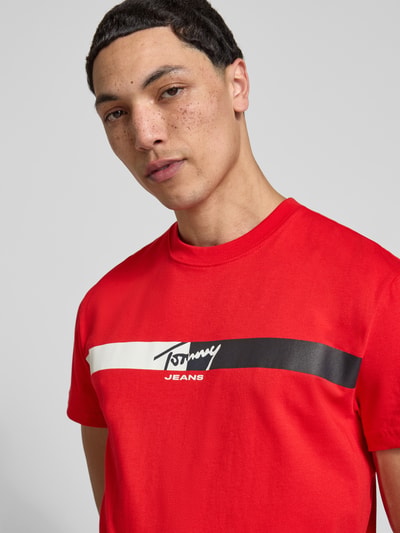 Männermodel trägt Regular Fit T-Shirt aus reiner Baumwolle von Tommy Jeans, unifarben, Label Print, Nahaufnahme Oberkörper.