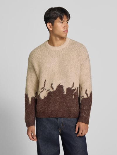 Männermodel trägt Strickpullover mit gerippten Abschlüssen von ANOTHER COTTON LAB, beige-braune Farben, lockere Struktur, ganzkörperansicht von vorne. Elastischer Material-Mix mit Lanawoll-Anteil, gerader Schnitt, Rundhalsausschnitt, überschnittene Ärmel, Rückenlänge 62 cm, Ärmellänge 67 cm.