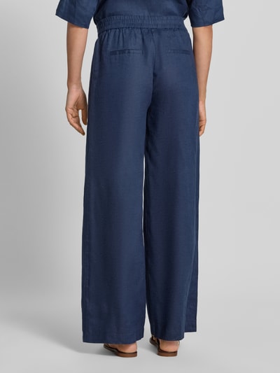 Frauenmodel trägt Leinenhose mit elastischem Bund von Emily Van den Bergh in Dunkelblau, Wide Leg Fit, seitliche Taschen, Ganzkörperansicht Rückansicht.