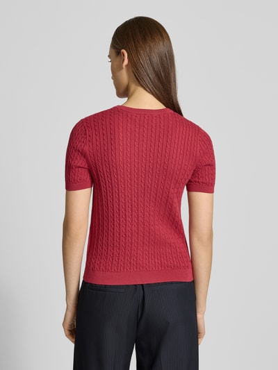 Frauenmodel trägt Kurzarmpullover mit Zopfmuster und Rundhalsausschnitt von Review, reine Baumwolle, Slim-Fit, Logo, Rippbündchen, Ganzkörperansicht Rückansicht.