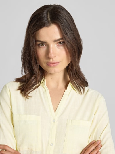 Vrouwenmodel draagt Regular Fit Hemdbluse aus reiner Baumwolle van Tom Tailor in effen lichtgeel, popeline met borstzakken, nahaufnahme bovenlichaam.