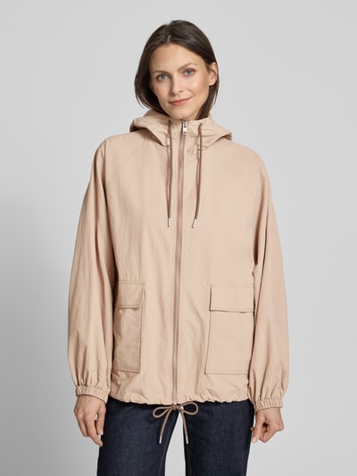 Vrouwenmodel draagt Jacke mit Kapuze und Pattentaschen van Jake*s Casual in beige met ritssluiting, klepzakken, relaxed fit, ruglengte maat 36: 66 cm, schouderbreedte: 41 cm, borstwijdte: 56 cm, mouwlengte: 65 cm, voorkant geheel zichtbaar, ganzkörperansicht van voren.