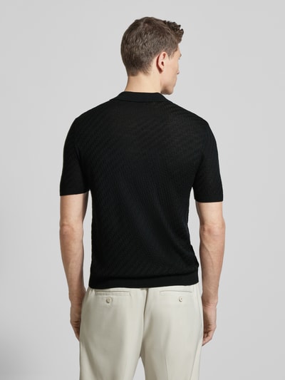 Männermodel trägt Slim Fit Poloshirt mit Lyocell-Anteil von Emporio Armani in Schwarz, Strick-Optik, Kurzarm, elastische Abschlüsse, Ganzkörperansicht Rückansicht.