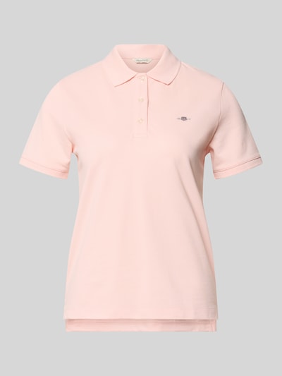 Frauenmodel trägt Poloshirt mit Logo-Stitching und Polokragen von Gant in zartem Rosa, Reine Baumwolle, Regular-Fit, kurze Knopfleiste, Rückenlänge bei Größe S 57 cm, Ganzkörperansicht von vorne.