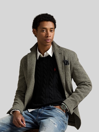Męski model nosi Regular Fit Strickpullover aus reiner Baumwolle od Polo Ralph Lauren, czarna jednolita faktura warkoczowa, logo, krój regular fit, okrągły dekolt, bawełniany materiał, widok na górną część ciała z przodu.