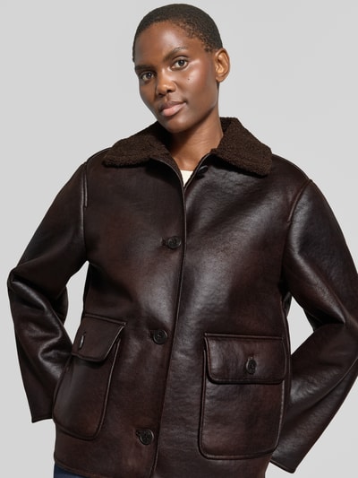 Vrouwenmodel draagt Regular Fit Webpelzjacke mit Leder-Optik van Jake*s Casual in donkerbruin met grove textuur, Nahaufnahme bovenlichaam.