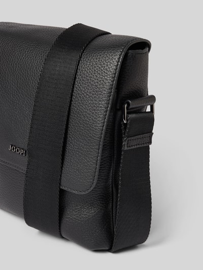 Produktfoto, Handtasche mit Schulterriemen Modell 'cardona flavio' von JOOP! Collection aus schwarzem, genarbtem Leder mit Label-Detail und Magnetverschluss, Maße: Breite 20 cm, Länge 22 cm, Tiefe 5 cm, Schulterriemen 101 cm.