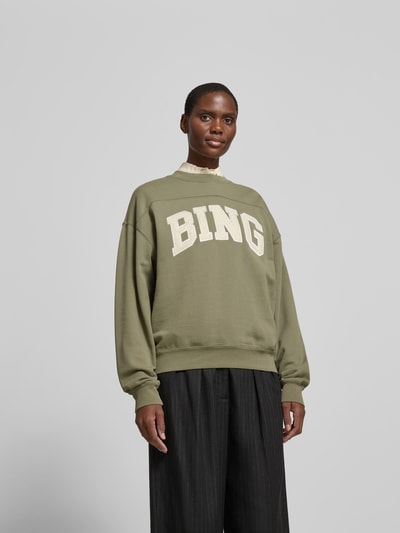 Frauenmodel trägt Oversized Sweatshirt aus Baumwolle von Anine Bing in Khaki mit Rundhalsausschnitt, Label-Detail und elastischen Abschlüssen, Rückenlänge bei Größe S: 61 cm, Ganzkörperansicht von vorne.