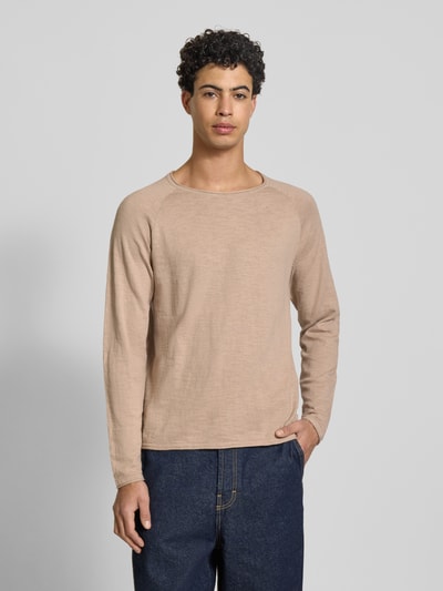 Męski model nosi Bluzka z długim rękawem Regular Fit Longsleeve mit Logo-Patch Model 'Breeze' od JACK & JONES z bawełny, imitacja dzianiny, okrągły dekolt, długość tyłu 65 cm, długość rękawów 69 cm, kolor beżowy, krój regular fit, naszywka z logo, całkowity widok z przodu.