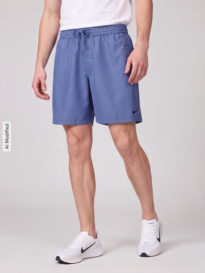 Männermodel trägt Regular Fit Sportshorts mit Logo-Print von Nike in Blau, glatte Struktur, Herren Sportshorts von Nike Training, Ganzkörperansicht von vorne, KI-modifiziertes Bild.